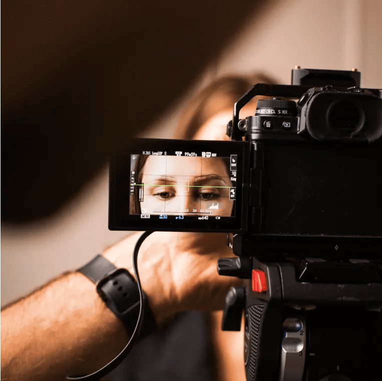 Mężczyzna filmujący kobietę czarną kamerą.